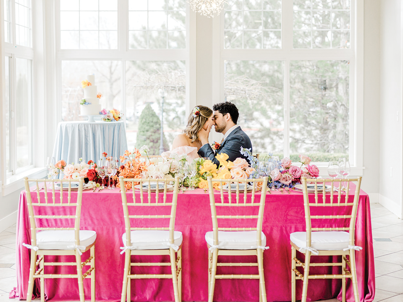 The bride and groom lean in for a kiss at a magenta wedding banquet table filled to the brim with colorful florals in the most vividly colorful wedding design we've ever curated. Custom color wedding florals professional wedding design unique wedding ideas and wedding inspo #luxurywedding #luxuryslcwedding #weddingplanner #boldwedding #colorfulwedding #pinkweddinginspo