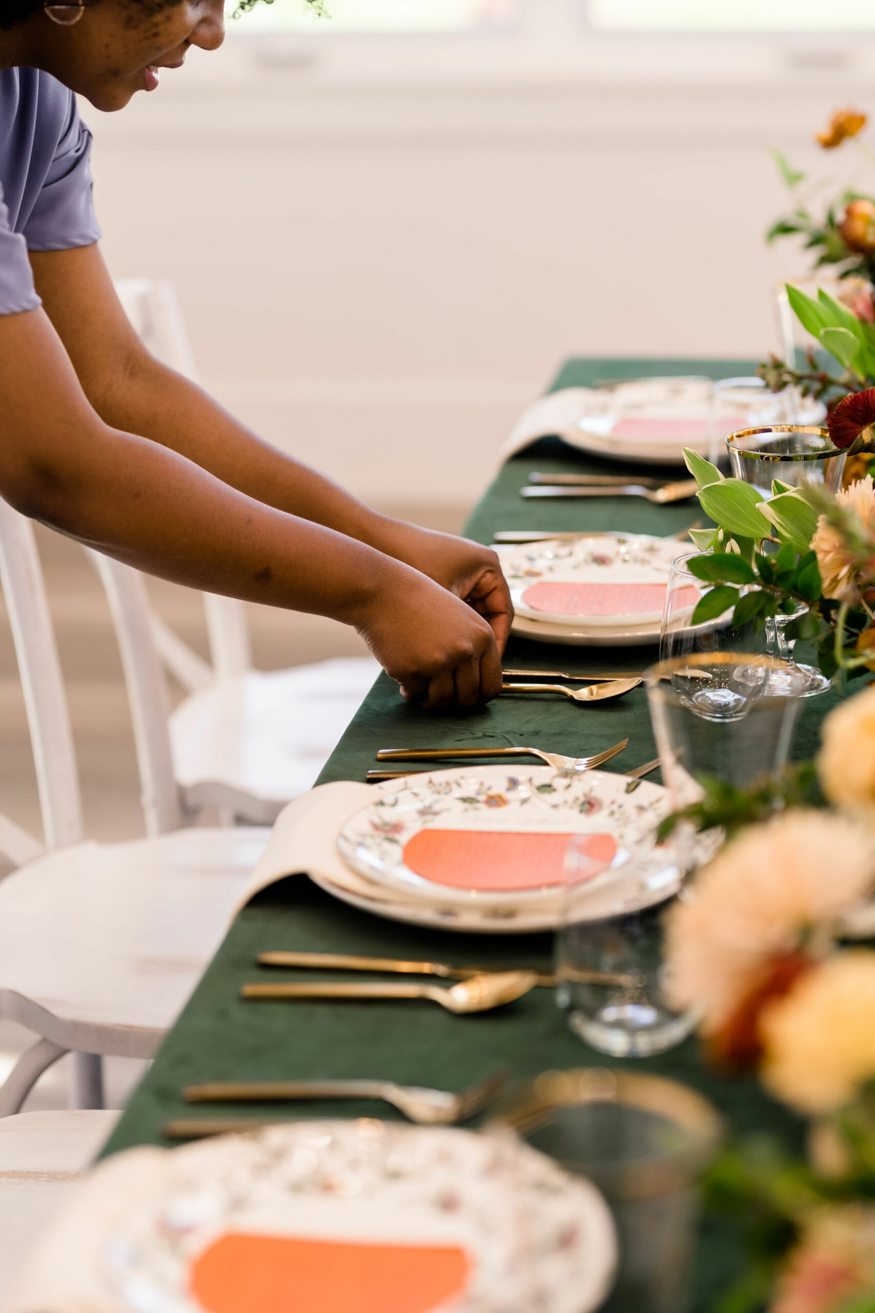 Place settings at a garden-themed baby shower coordinated by Utah event planners Kaushay & Co., with a green tablecloth, gold utensils, and pink accents. Baby shower theme ideas baby shower tablescape #babyshowerideas #eventplannerutah #luxuryeventplanner #babyshower