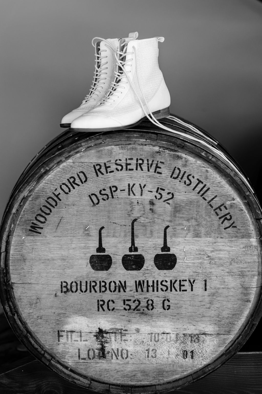 Black and white photo of hightop wedding shoes on top of a barrel of bourbon at a unique wedding planned by Kaushay & Co. #weddingplanningtips #utahweddingplanners #luxuryweddingservices #midwestweddingplanner #eventplannersiniowa #northcarolinabrides #slcweddings
